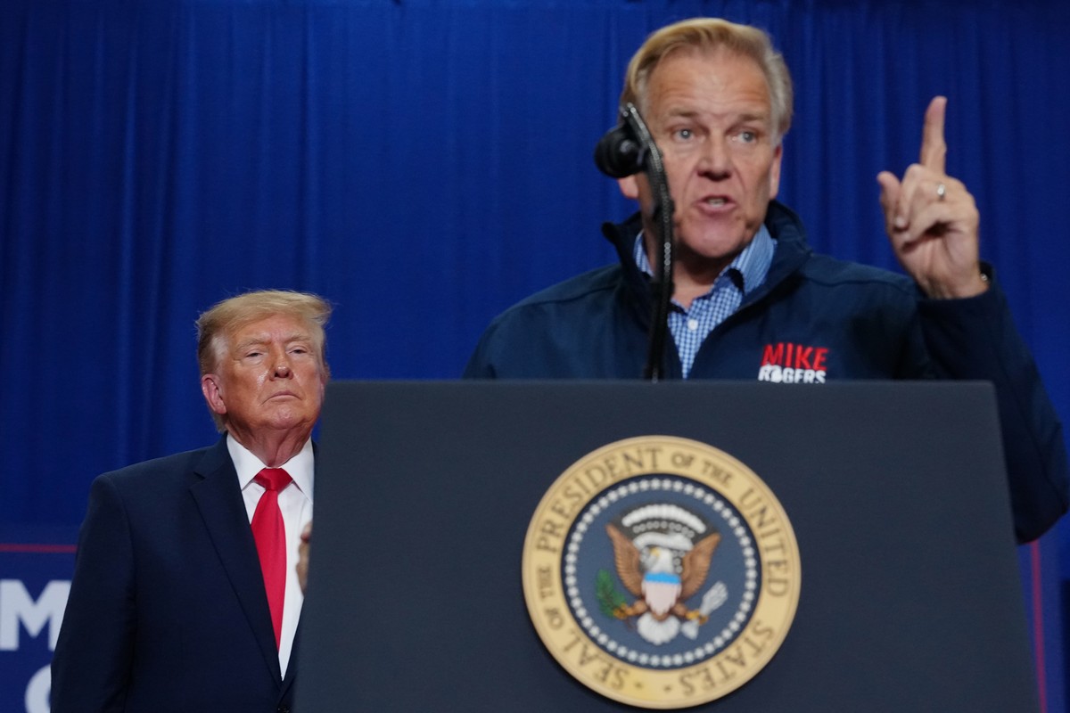 President Donald Trump, left, listens as Mike Rogers, a Michigan Republican candidate for Senate, right, speaks during a campaign rally at McMorran Place Sports and Entertainment Center, Sunday, Oct.  ...