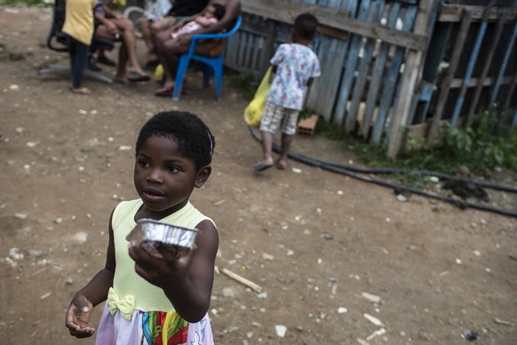 A child holds a container of donated food in the Jardim Gramacho favela of Rio de Janeiro, Brazil, Saturday, Oct. 30, 2021, delivered by volunteers for the non-governmental organization &quot;Covid Se ...