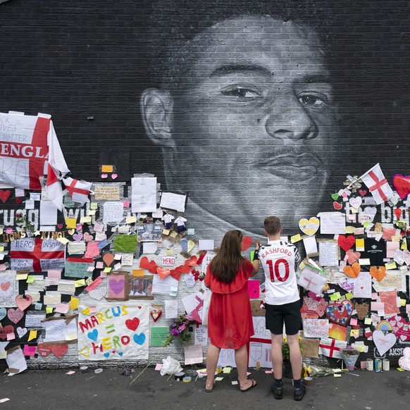 Mackenzie Robertson aged 15 and his mother Sally Coles-Roberton place a message of support on a mural of Manchester United striker and England player Marcus Rashford, on the wall of the Coffee House C ...