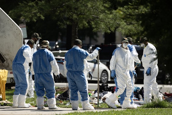 epa11345564 Workers collect tents and other objects and place them into a garbage truck to be destroyed during a removal and cleanup of an encampment occupied by people experiencing homelessness, in W ...