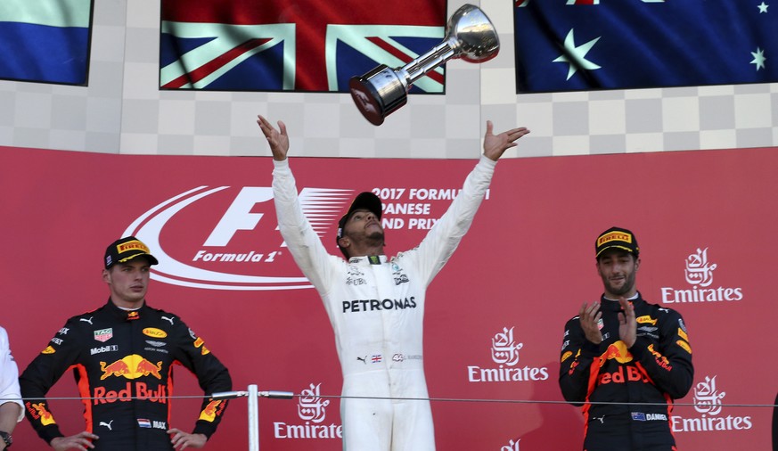 Mercedes driver Lewis Hamilton of Britain throws his trophy as he celebrates on the podium after winning the Japanese Formula One Grand Prix at Suzuka, Japan, Sunday, Oct. 8, 2017. Second placed Red B ...