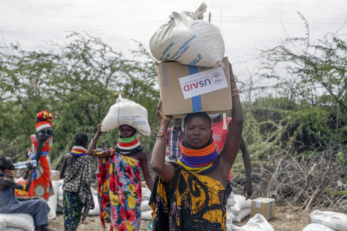 Locals residents carry a boxes and sacks of food distributed by the United States Agency for International Development (USAID), in Kachoda, Turkana area, northern Kenya, Saturday, July 23, 2022. Saman ...