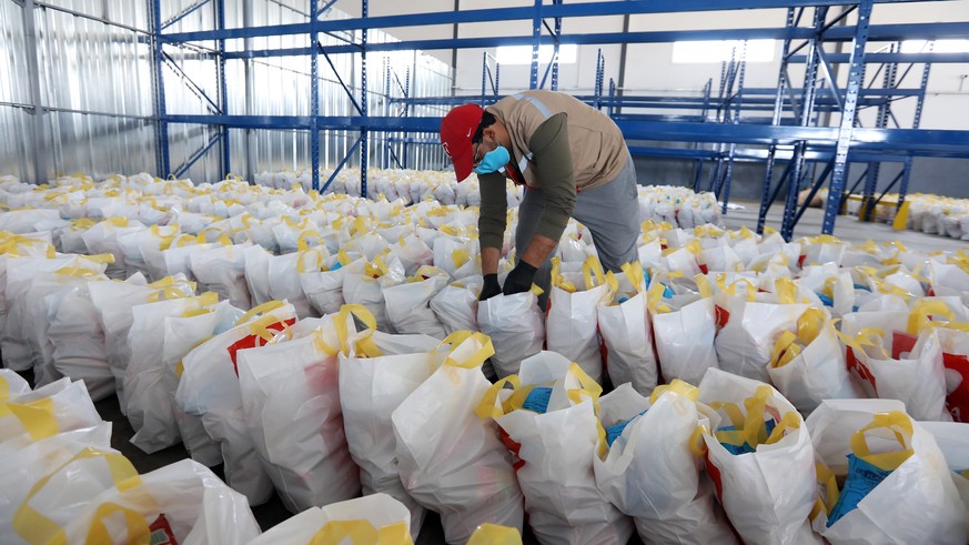 epa08334964 A Tunisian Red Crescent member prepares food packages to be delivered to the elderly and needy families during the ongoing emergency measures over the ongoing pandemic of the novel coronav ...