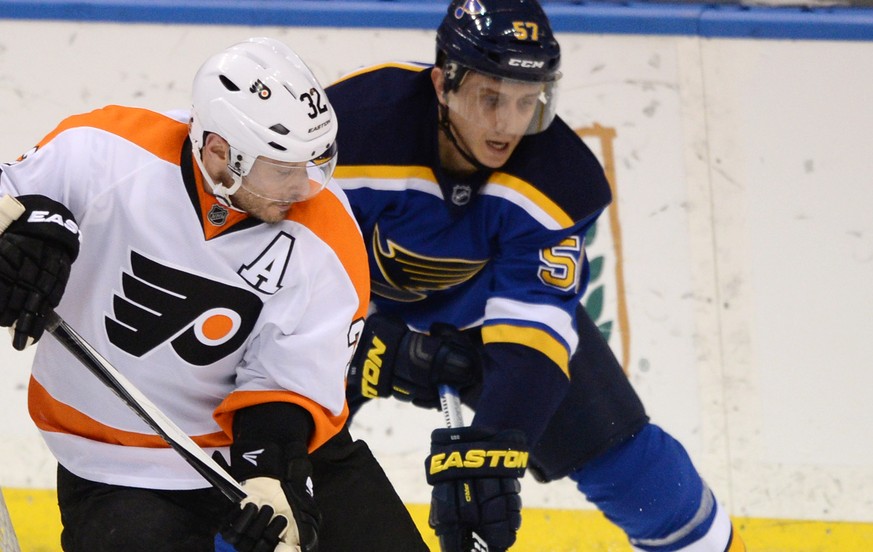 Philadelphia Flyers&#039; Mark Streit (32), of Switzerland, and St. Louis Blues&#039; Marcel Goc (57), of Germany, reach for the puck during the second period of an NHL hockey game, Thursday, March 12 ...