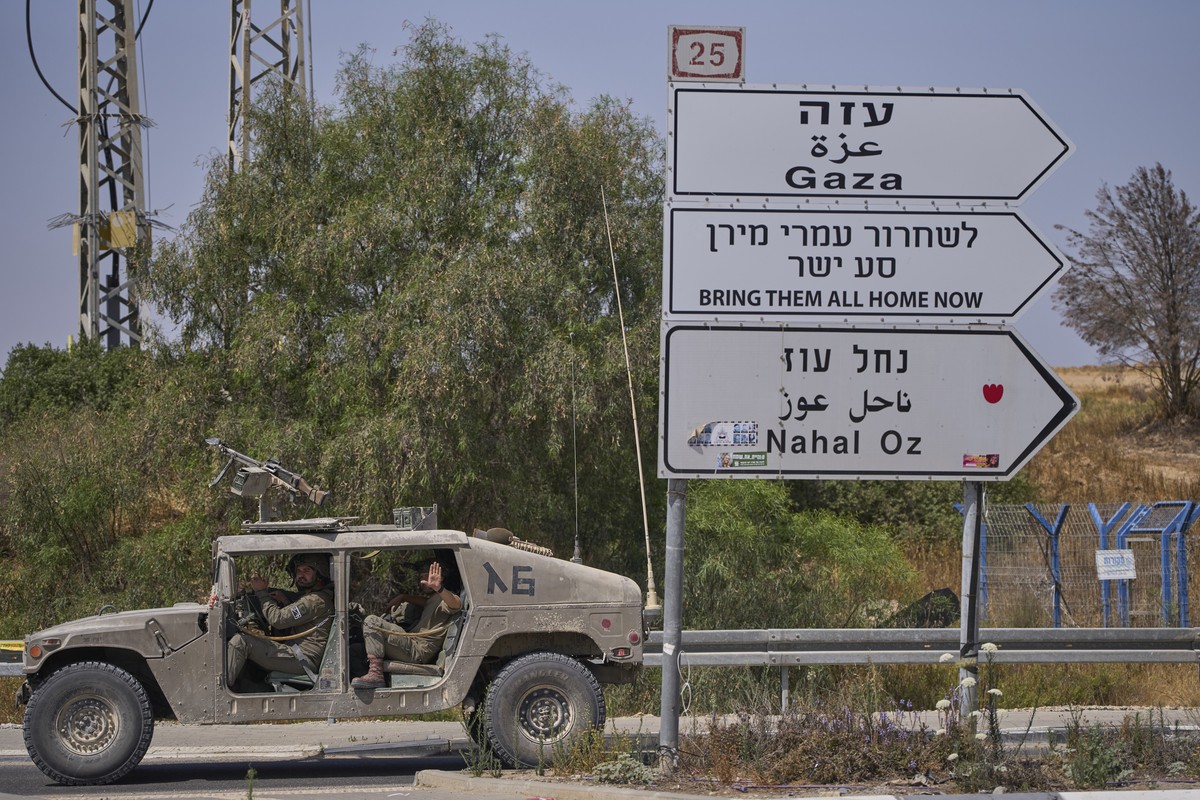 Israeli army vehicle pass by a new sign pointing towards Gaza reading "To release Omri Miron go straight" near Kibbutz Nahal Oz in southern Israel, where Miron was kidnapped from on Oct. 7,  ...