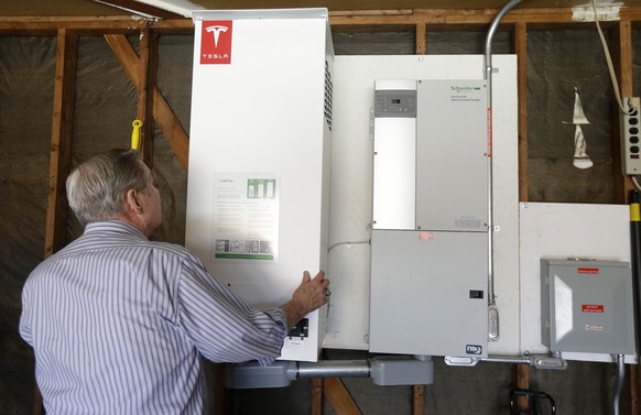 In this April 20, 2015 photo, David Cunnigham shows a prototype Tesla battery system that powers his Foster City, Calif. home. Cunnigham installed the battery late last year to pair with his solar pan ...