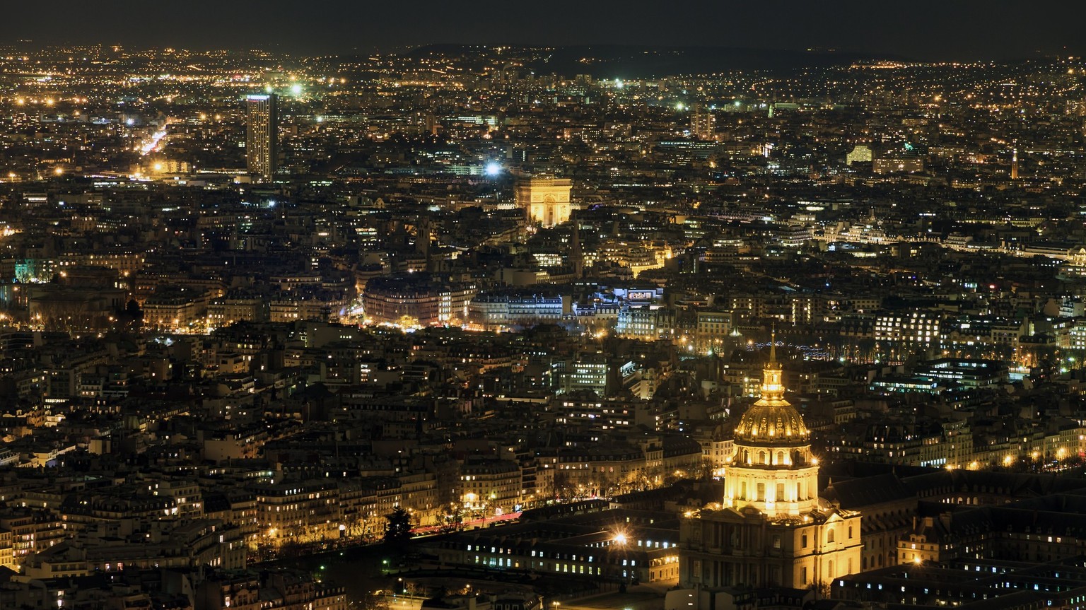 Beautiful aerial cityscape of Paris, France, at night with the Dome des Invalides and the Arc de Triomph