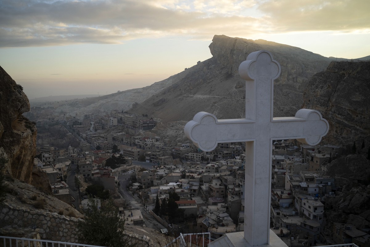Houses are seen along the mountain as a cross stands over the Greek Orthodox convent Saint Takla on Christmas Eve in Maaloula, some 60 km northern Damascus, Syria, Tuesday, Dec. 24, 2024. (AP Photo/Le ...