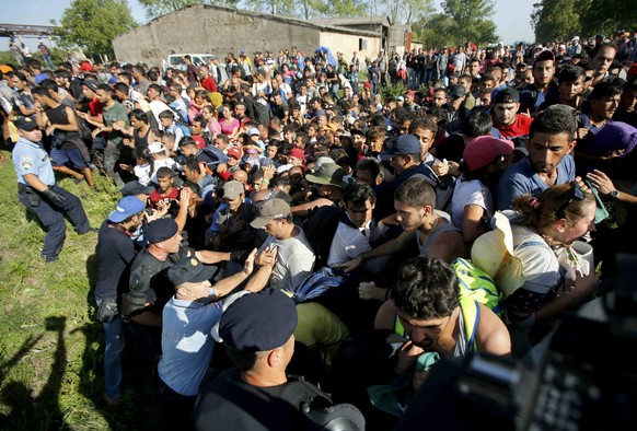 Migrants push policemen during a stampede to board buses in Tovarnik, Croatia September 17, 2015. Croatia said on Thursday it could not take in any more migrants, amid chaotic scenes of riot police tr ...