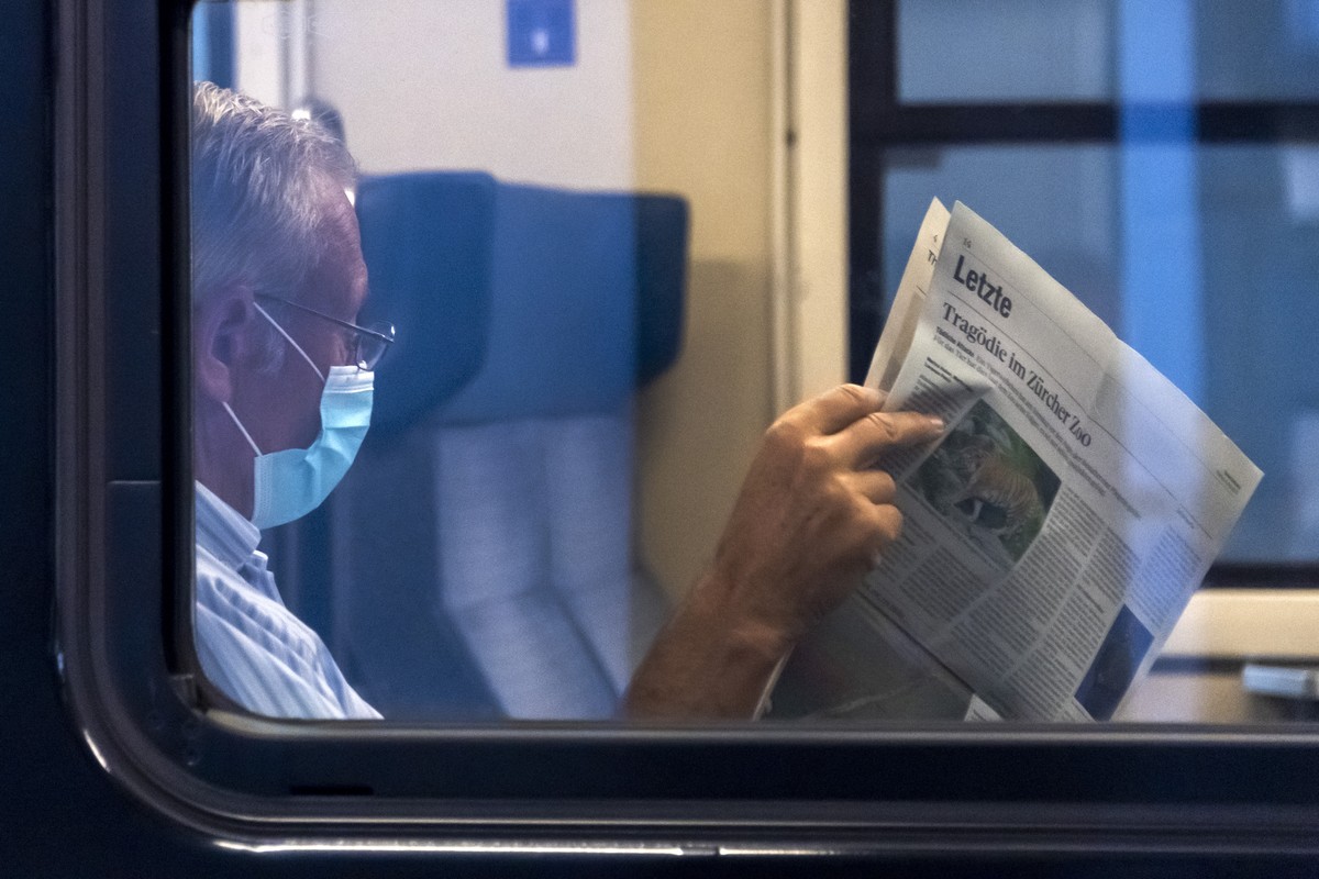 Ein Reisender mit Schutzmaske liest Zeitung in einem Zug am Bahnhof SBB in Basel, am Montag, 6. Juli 2020. Das Schutzkonzept gegen das Coronavirus wurde angepasst: Alle Reisenden muessen in oeffentlic ...