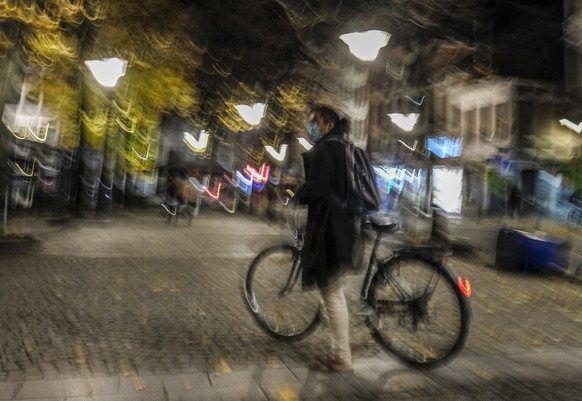 epa08771259 A man with his bike in a almost empty street before a city night time curfew scheduled at 22h in Liege, Belgium, 24 October 2020. Walloon region announced on 23 October a curfew from 22h u ...