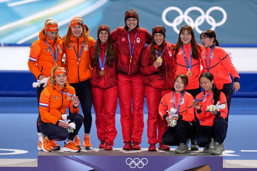 Team Canada, center and gold medal, team Netherlands, left and silver medal, and team Japan, right and bronze medal, celebrate on the podium of the women's team pursuit speedskating race at the 2 ...