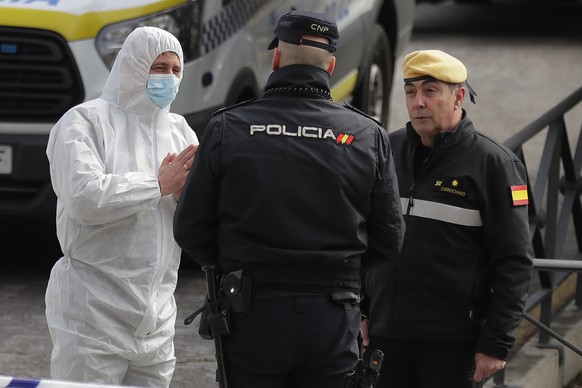 A member of UME, left, talks with a police officer at a ice-skating rink in Madrid, Spain, Tuesday, March 24, 2020. Madrid&#039;s ice-skating rink is now being used as a makeshift morgue given the rap ...