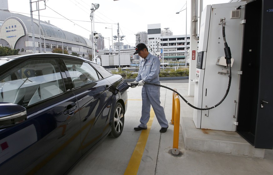 In this photo taken Monday, Nov. 17, 2014, a fuel cell charge station worker demonstrates how to charge hydrogen to a Toyota Motor Corp.'s new fuel cell vehicle Mirai at a charge station near Toyota's ...