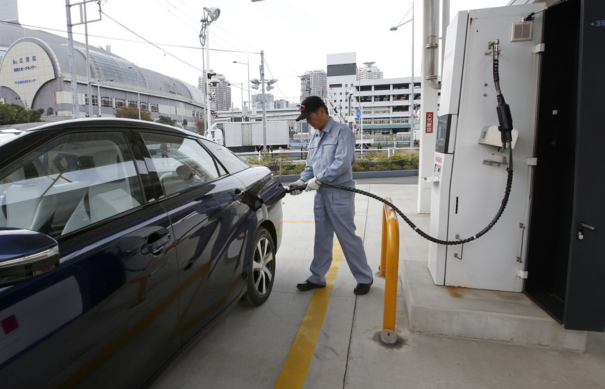 In this photo taken Monday, Nov. 17, 2014, a fuel cell charge station worker demonstrates how to charge hydrogen to a Toyota Motor Corp.&#039;s new fuel cell vehicle Mirai at a charge station near Toy ...