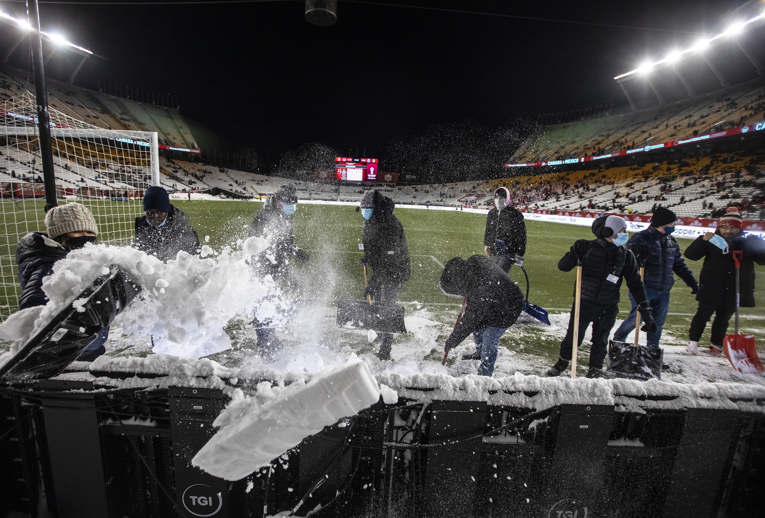 Crews clean snow off the field before a FIFA World Cup qualifying soccer match between Canada and Mexico, Tuesday, Nov. 16, 2021, in Edmonton, Alberta. (Jason Franson/The Canadian Press via AP)