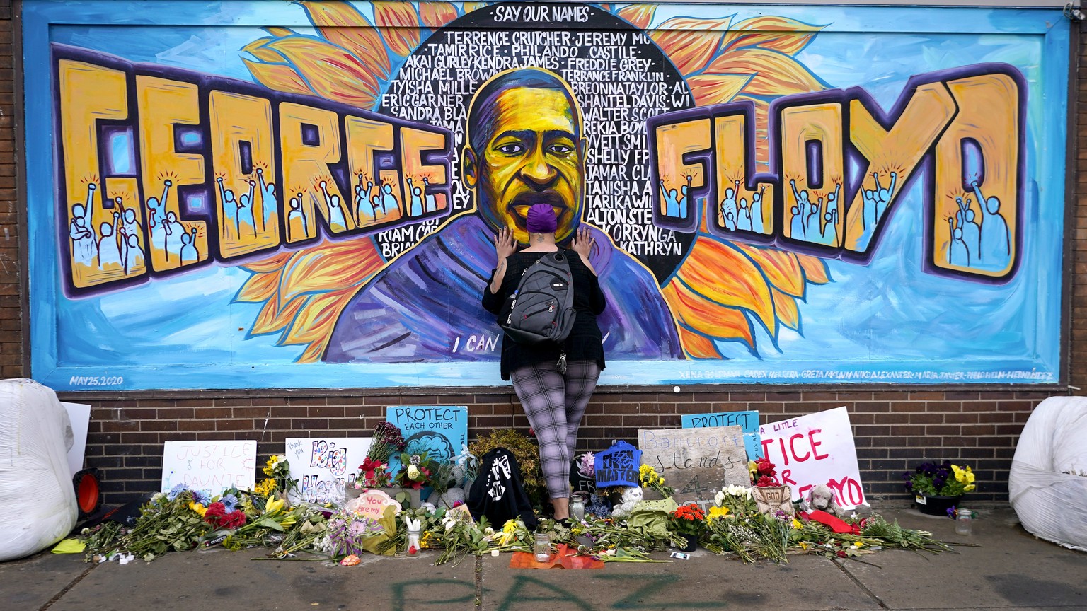 FILE - In this Friday, April 23, 2021 file photo, Damarra Atkins pays respect to George Floyd at a mural at George Floyd Square in Minneapolis. Newly released video that shows Minneapolis police offic ...