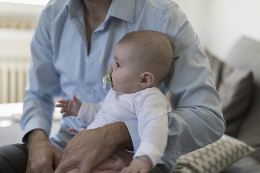 ZUM THEMA VATERSCHAFTSURLAUB STELLEN WIR IHNEN HEUTE, MITTWOCH, 25. OKTOBER 2017, FOLGENDES BILDMATERIAL ZUR VERFUEGUNG --- A father sits on the sofa with his five-month-old daughter, pictured in Kilc ...