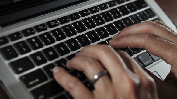 FILE- In this June 19, 2017, file photo, a person types on a laptop keyboard in North Andover, Mass. A new report by a global media consortium that expands the known target list of the Israeli hacker- ...
