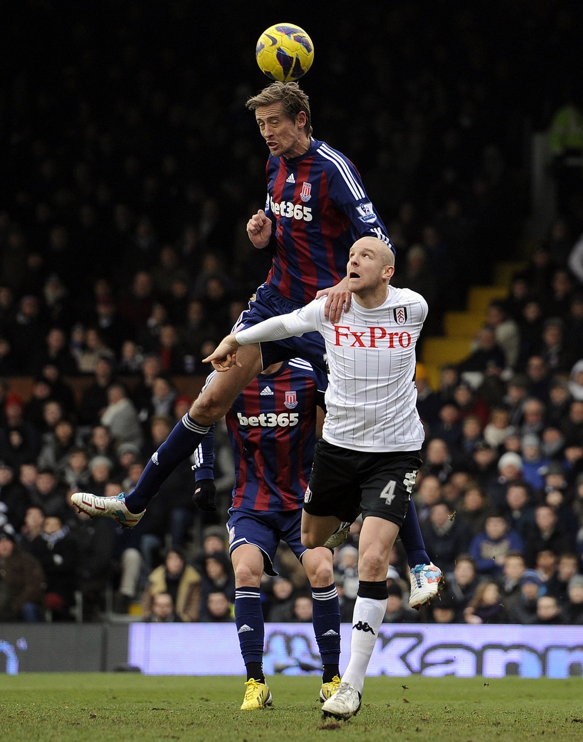 Stoke City's Peter Crouch , centre, heads the ball above Fulham's Philippe Senderos during the English Premier League match at Craven Cottage, London, Saturday Feb. 23, 2013. (AP Photo/PA, J ...