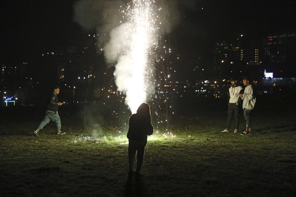 People light a firework while celebrating Chaharshanbe Souri, or Wednesday Feast, an ancient Festival of Fire, on the eve of the last Wednesday of the solar Persian year, in Tehran, Iran, Tuesday, March 15, 2022. While approaching the Iranian New Year, people across the country, light bonfires, set off fireworks sending wish lanterns into the night sky during the annual ritual that dates back to at least 1700 B.C. and is linked to Zoroastrianism in the Persian Empire. (AP Photo/Vahid Salemi)