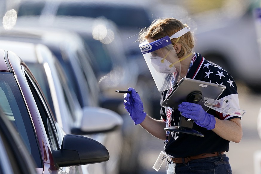 An election worker instructs a voter at a drive-through polling location Tuesday, Nov. 3, 2020, in Kansas City, Mo. The location was established to provide access for people who have tested positive f ...