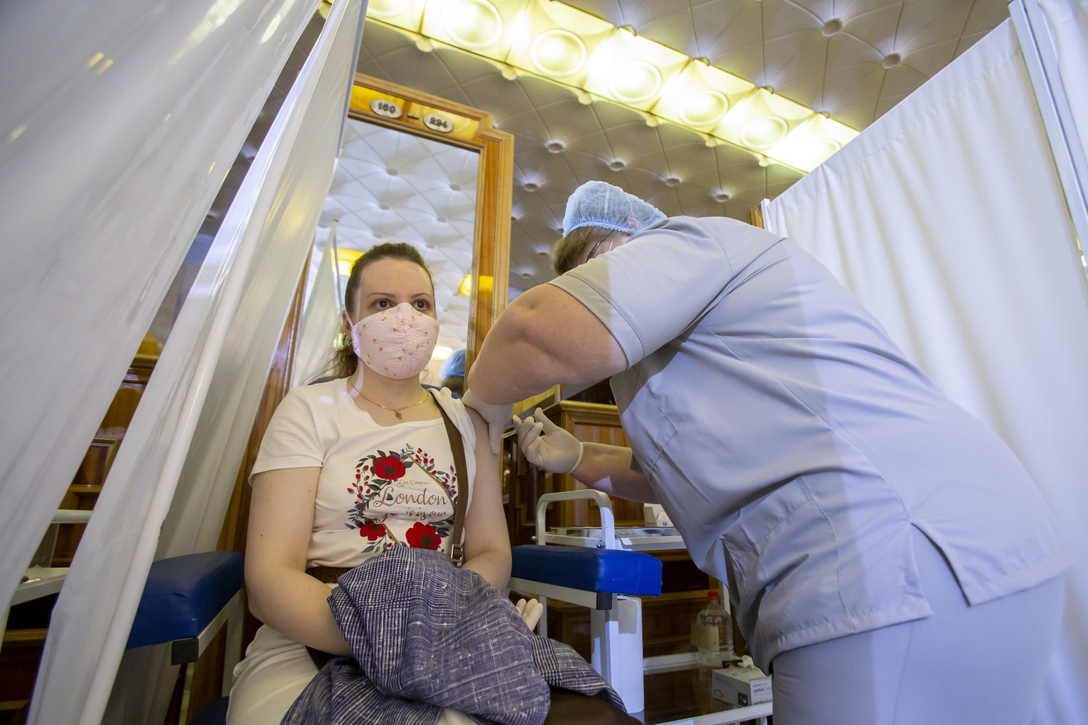 epa09302692 A health worker administers a dose of Russia&#039;s Sputnik V (Gam-COVID-Vac) vaccine against COVID-19 to a woman at the vaccination point in the warderobe zone at the Republican Palace in ...