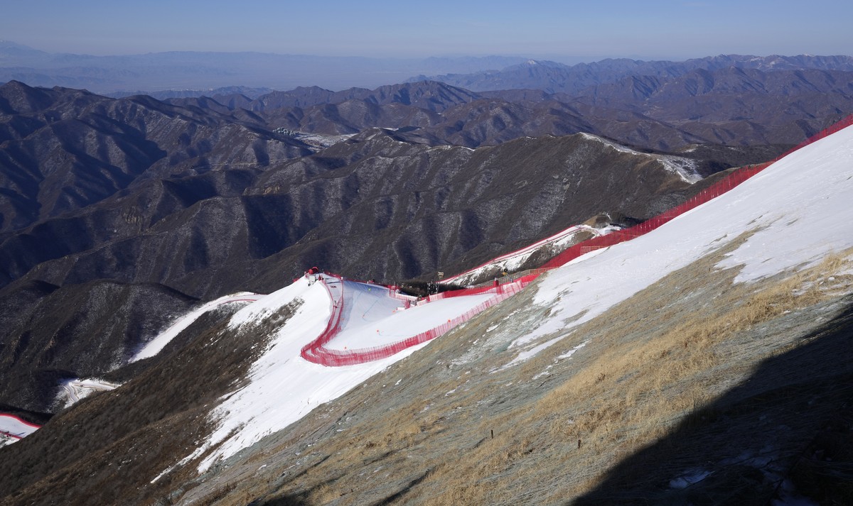 The downhill course stands out from the almost snowless landscape ahead of the first men's downhill training run at the 2022 Winter Olympics, Thursday, Feb. 3, 2022, in the Yanqing district of Be ...