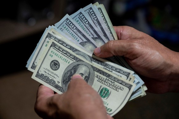 epa08577313 A man counts a wad of dollar bills in Caracas, Venezuela, 30 July 2020 (issued 31 July). The unstoppable inflation that Venezuela is experiencing has led to the inevitable de facto dollari ...