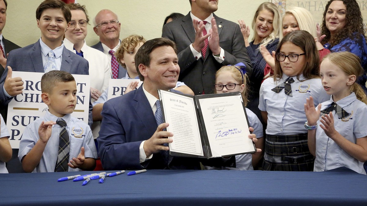 Florida Gov. Ron DeSantis displays the signed Parental Rights in Education, aka the Don't Say Gay bill, flanked by elementary school students during a news conference on Monday, March 28, 2022, a ...