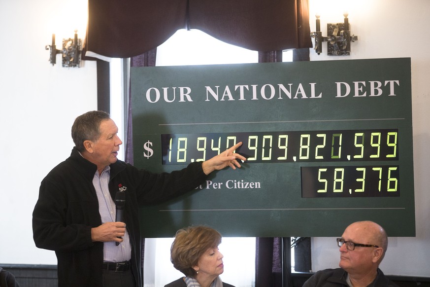 Republican presidential candidate Ohio Gov. John Kasich, left, points to a digital national debt clock during a campaign stop at VFW Post 8641, Saturday, Jan. 30, 2016, in Merrimack, N.H. (AP Photo/Jo ...