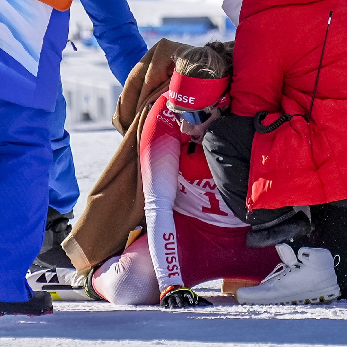 epa09761553 Irene Cadurish (bottom) of Switzerland receives medical attention during the Women's Biathlon 4x6km Relay race at the Zhangjiakou National Biathlon Centre at the Beijing 2022 Olympic  ...