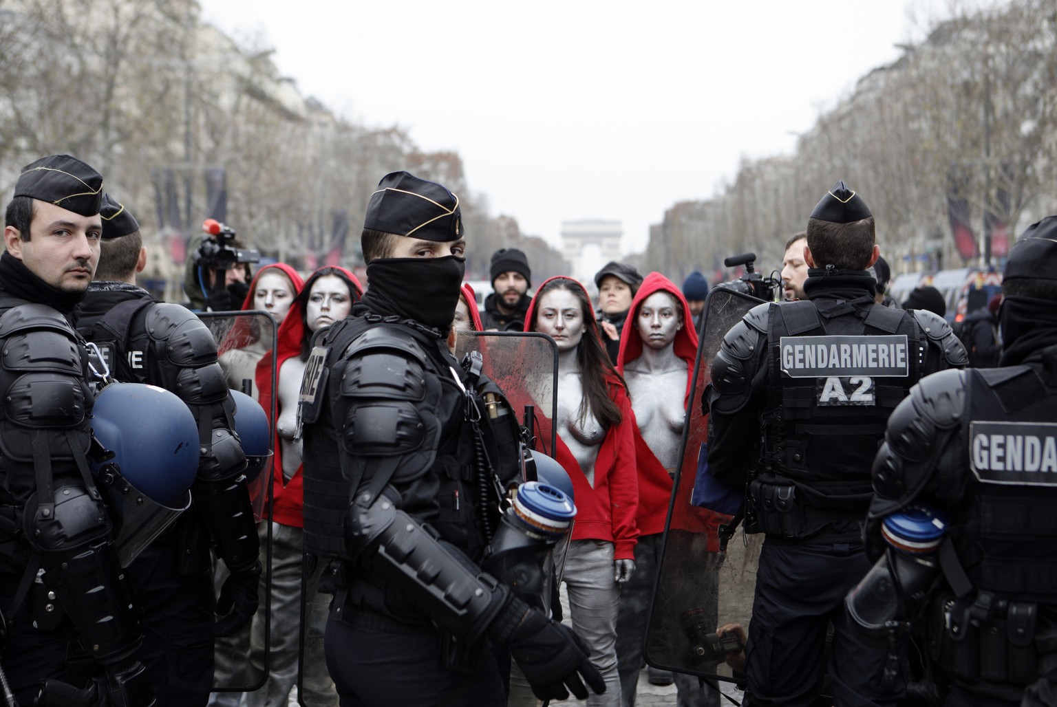EDS NOTE : NUDITY. Activists dressed like Marianne, symbol of the French Republic, face riot police officers during a yellow vests protest Saturday, Dec. 15, 2018 in Paris. French President Emanuel Ma ...