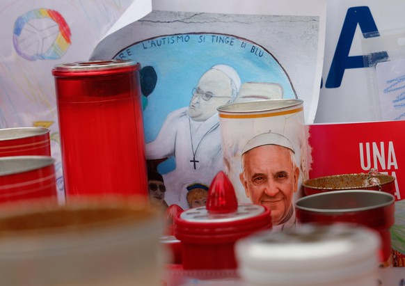 epa11947292 Candles and drawings with the pictures of Pope Francis are placed under the statue of late Pope John Paul II outside Agostino Gemelli Hospital where Pope Francis is hospitalized to continu ...