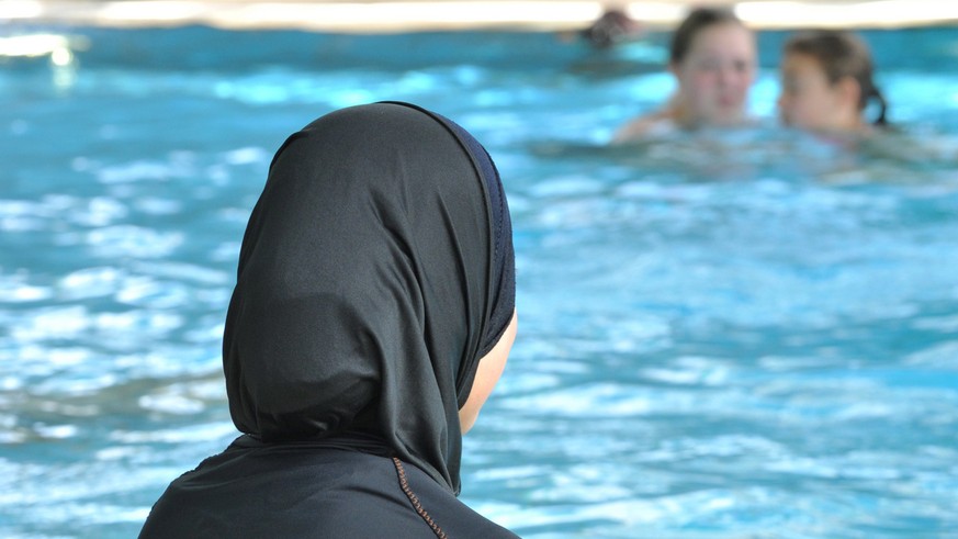 ARCHIV - Eine muslimische Schülerin sitzt am 23.06.2009 in einem Ganzkörper-Badeanzug (Burkini) am Rande eines Schwimmbeckens. Zwei muslimische Eltern aus Basel wehren sich vor dem Europäischen Mensch ...