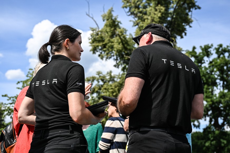 epa10753725 Tesla workers speak with local residents during Tesla Gigafactory promoting event at Hangelsbeg near Berlin, Germany, 18 July 2023. Tesla plans to expand its Gigafactory by doubling produc ...