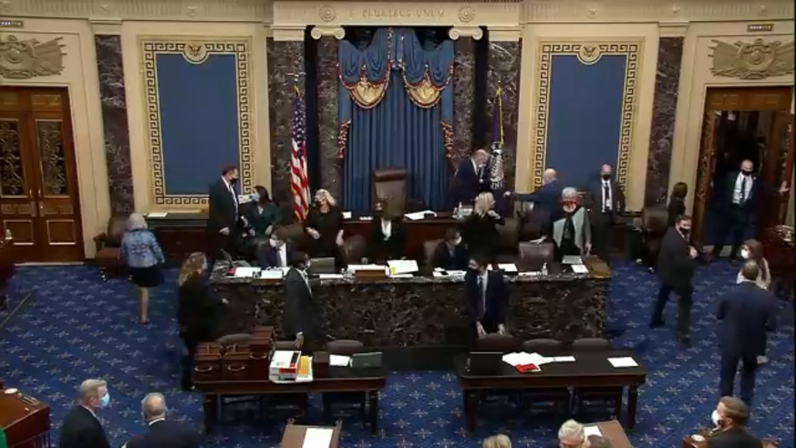 epa08923464 A frame grab from video made available by the United States Senate TV shows the moment before the Senate went into recess as members evacuate due to protesters storming the Capitol, during ...