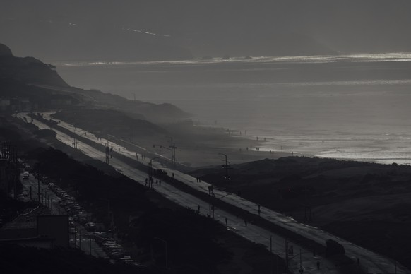 People walk along Upper Great Highway and Ocean Beach during a brief sun break in San Francisco, Saturday, Dec. 21, 2024. (Stephen Lam/San Francisco Chronicle via AP)
