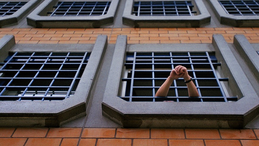 Ein Haeftling der Kantonalen Strafanstalt Poeschwies in Regensdorf (ZH) hat am 15. Dezember 2003 das Fenster seiner Zelle geoeffnet und stuetzt seine Arme auf dem Gitter ab. (KEYSTONE/Gaetan Bally) :  ...