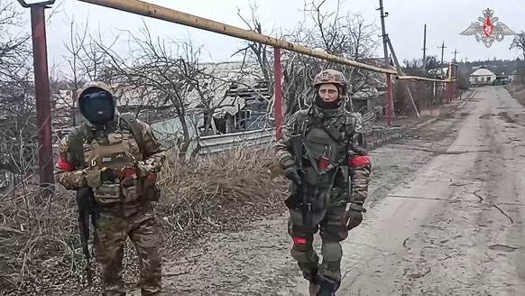 FILE - In this photo released by Russian Defense Ministry Press Service on Feb. 19, 2024, Two soldiers of the Russian military engineering units walk after eliminating the mine danger in the city of A ...