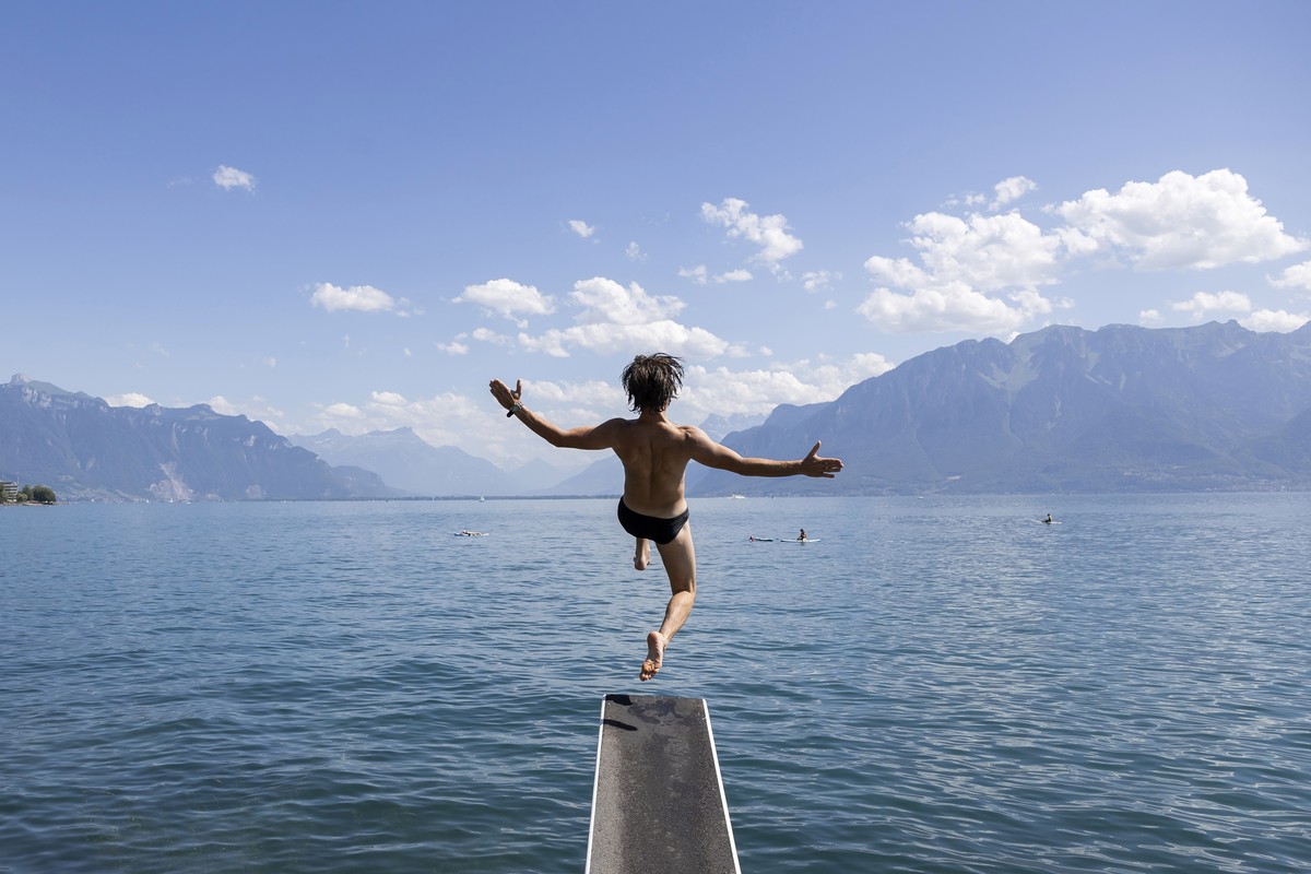 epa10734761 A man jumps into the lake on a warm summer day on the shores of Lake Geneva in front of the Swiss Alps mountains, in Vevey, Switzerland, 08 July 2023. EPA/CYRIL ZINGARO