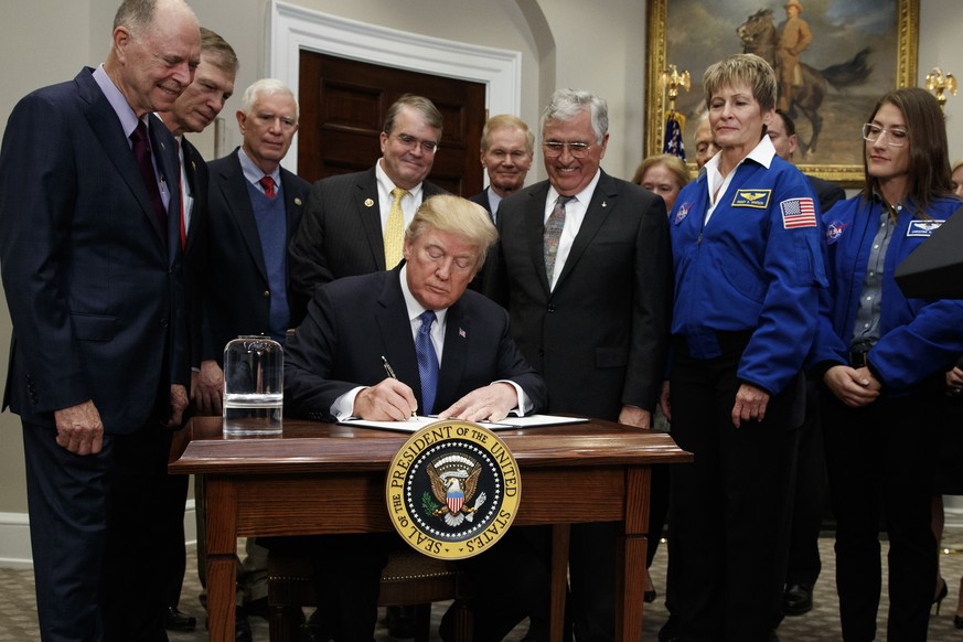 President Donald Trump signs a policy directive to send American astronauts back to the moon, and eventually Mars, in the Roosevelt Room of the White House, Monday, Dec. 11, 2017, in Washington. (AP P ...