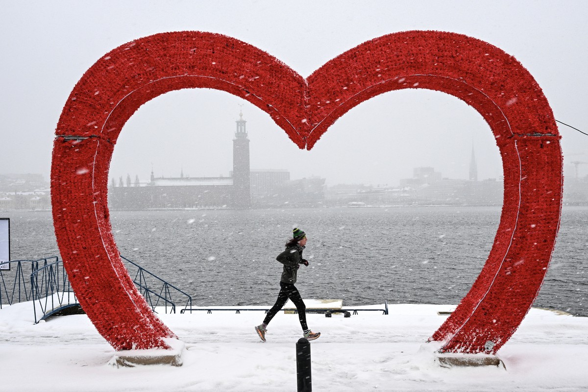 epaselect epa11053722 A runner jogs past a heart-shaped installation, with Stockholm City Hall in the background, during a snowfall in Stockholm, Sweden, 02 January 2024. Snow and slippery conditions  ...