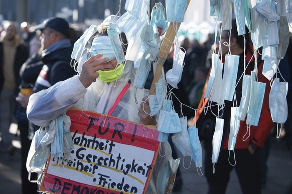 A participant carries a sign reading 'For you! Truth, Justice, Liberty and peace' in the demonstration of the Stuttgart initiative "Lateral Thinking" is standing on Augustusplatz w ...