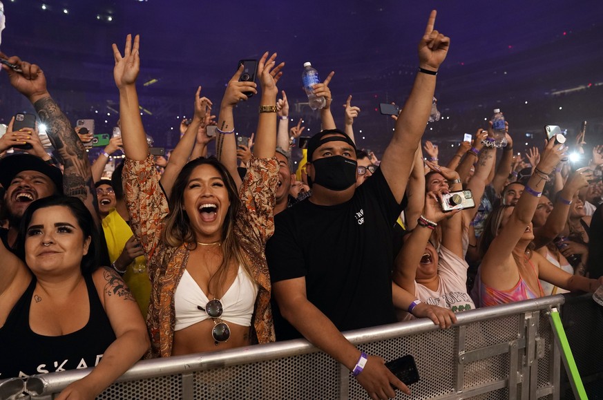 A masked fan is surrounded by unmasked fans during Kaskade&#039;s performance at SoFi Stadium, Saturday, July 17, 2021, in Los Angeles. (AP Photo/Chris Pizzello)