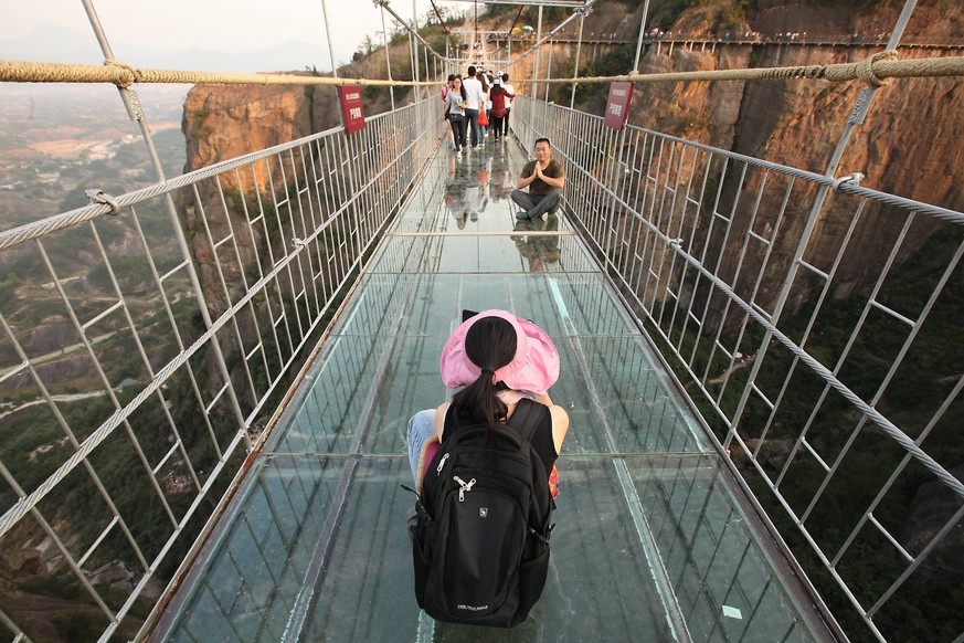 Hundreds of Chinese tourists visit a recently completed glass-bottomed bridge nearly 600 yards above a sheer drop in Shiniuzhai Park in northern Hunan Province, China, on October 24, 2015. Haohan Qiao ...