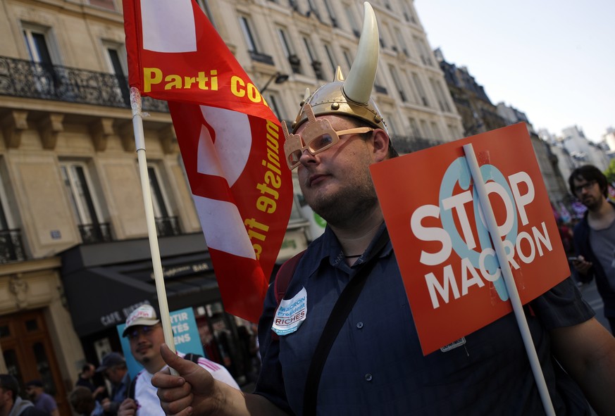 A protester caries French Communist Party flag in Paris, France, Saturday, May 5, 2018. Activists are calling for calm Saturday as the French capital prepares for a what they are calling a mass &quot; ...