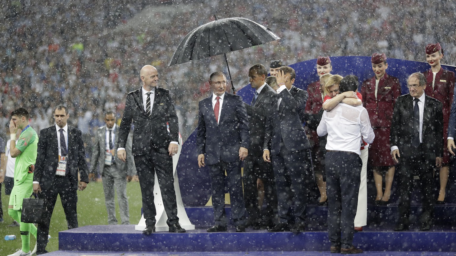 FIFA President Gianni Infantino, third left, gestures as Russian President Vladimir Putin stands underneath an umbrella as Croatian President Kolinda Grabar-Kitarovic greets Croatia head coach Zlatko  ...