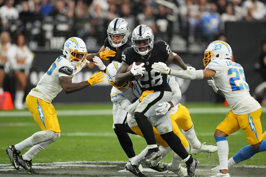 Las Vegas Raiders running back Josh Jacobs (28) carries between Los Angeles Chargers cornerback Asante Samuel Jr. (26) and cornerback Bryce Callahan (23) during the second half of an NFL football game ...