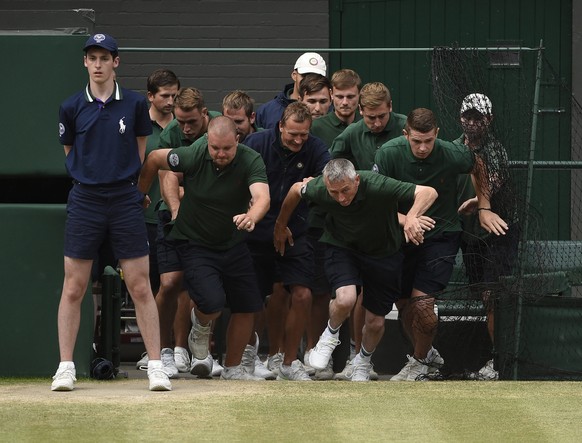 epa04844168 Grounds staff rush onto Centre Court as rain interrupts the men&#039;s final of the Wimbledon Championships at the All England Lawn Tennis Club, in London, Britain, 12 July 2015. EPA/FACUN ...